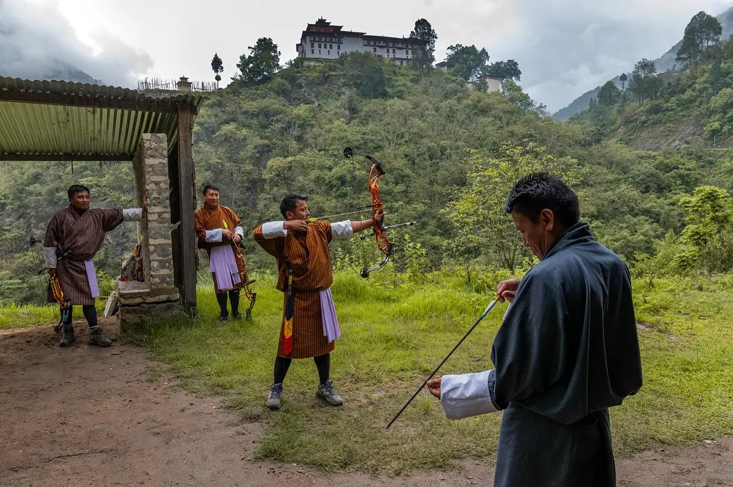 Bhutanese men competing in traditional archery — the national sport around which community feasts and shared meals are traditionally held