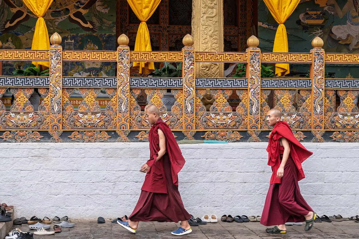 Monks in crimson robes gathered at a Bhutanese monastery — the spiritual community life that forms the foundation of Bhutanese contentment