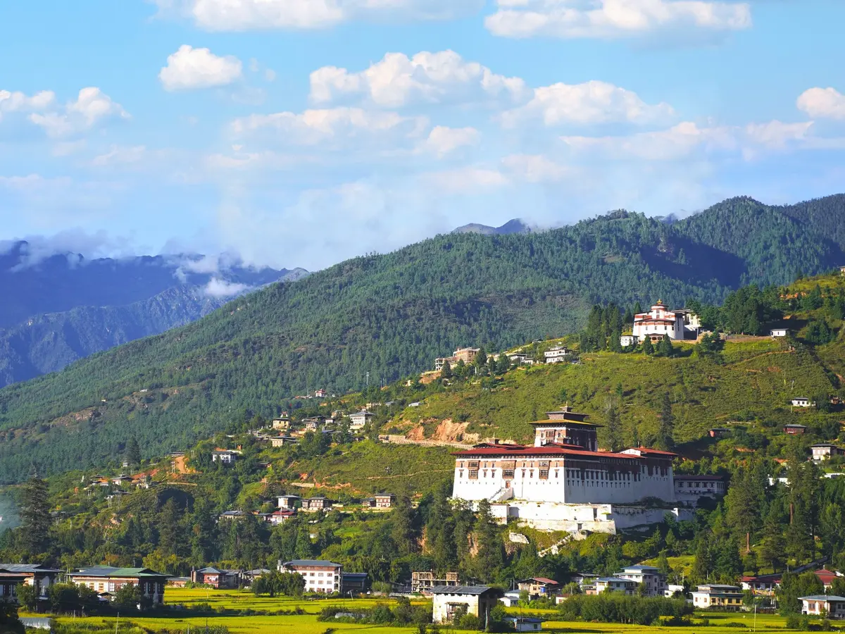 Paro valley in Bhutan with traditional farmhouses and terraced fields framed by steep forested ridgelines
