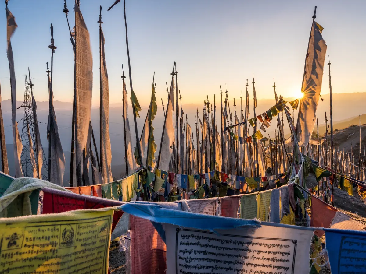 Prayer flags strung across a Bhutanese mountain pass — crossing into the kingdom is easier than its reputation suggests
