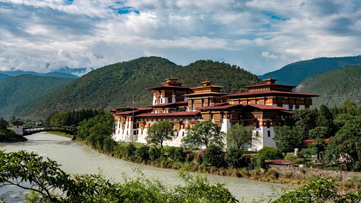 Punakha Dzong viewed in daylight from across the river — its tiered white walls and golden rooftops the pinnacle of nail-free Bhutanese architectural tradition